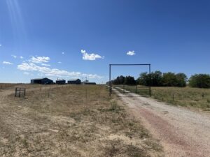 A metal entrance gate and archway leading to a property, a completed project by Cool Hand Fencing and Wyo War Wagons in Laramie, WY.