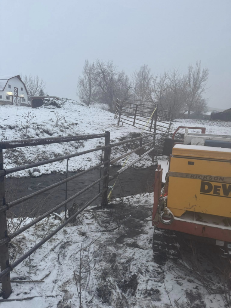 A durable metal fence and gate system installed over a stream by Deer Creek Ag Services in Ranchester, WY.