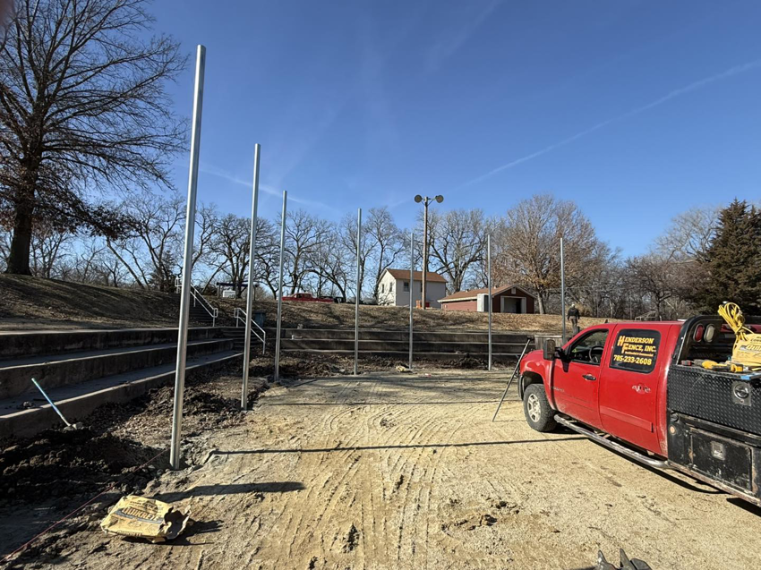 Metal fence posts being installed around a sports field, with a Henderson Fence, Inc. truck on site in Culpeper, VA.
