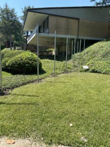 Metal fence posts installed on a sloped grassy yard, indicating a fence installation in progress by EverFence in Dallas, TX.