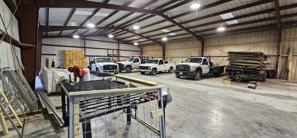 A worker fabricating a metal gate frame in a workshop, demonstrating custom fence solutions by Fence Builders of Houston, TX.