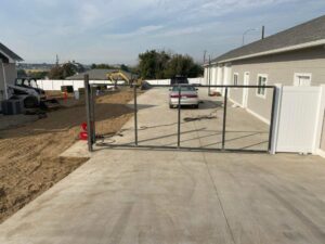 A metal gate frame being installed next to a white vinyl fence by Integrity Gates and Fencing in Yakima, WA
