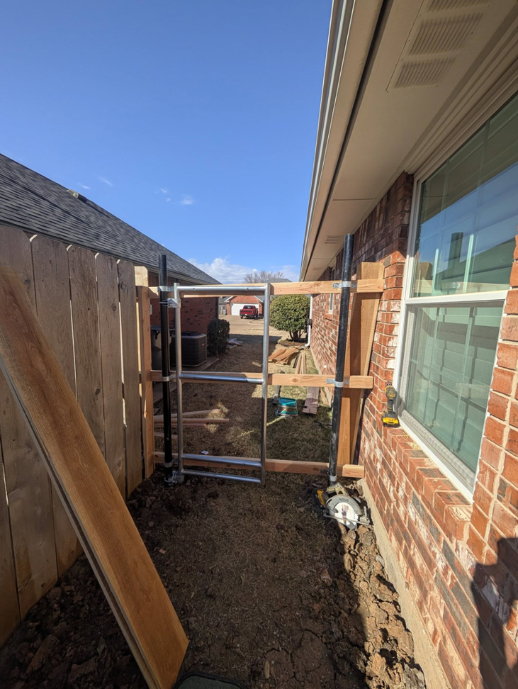 Installation of a metal gate frame in a narrow side yard by Black and Sons fencing in Indiahoma, OK.