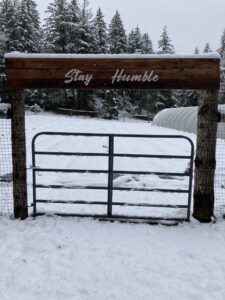 A metal gate with wooden posts and a sign in a snowy landscape by Olson Handyman Services, LLC in New Braunfels, TX