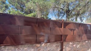 A metal privacy fence with a stone wall base by Iron Man Exteriors in Las Cruces, NM.