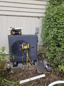 A Midea heat pump unit undergoing installation or service with gauges and a vacuum pump by Conrad Heating and Cooling in Beaverton, OR.