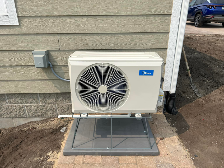 An outdoor Midea HVAC unit newly installed next to a residential building by BRY Heat and Air in Elgin, MN