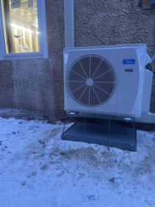An outdoor Midea heat pump unit installed in winter conditions by BRY Heat and Air in Elgin, MN