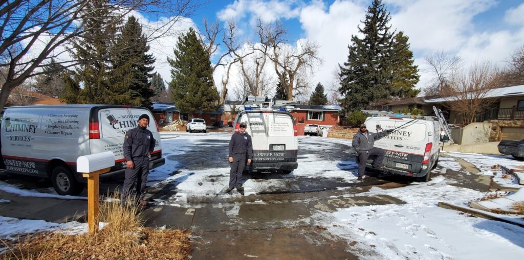 The Midtown Chimney Sweeps team with their service vans in a snowy residential neighborhood in Golden, CO.