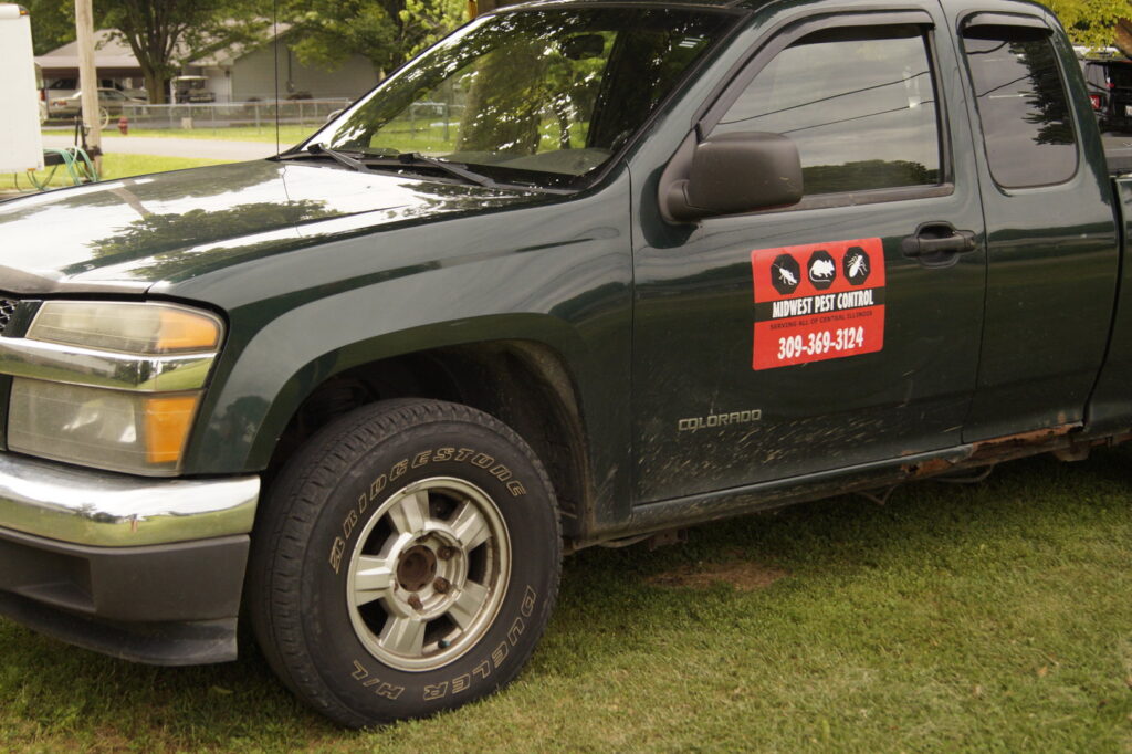 A green service truck with the Midwest Pest Control logo and contact information, serving clients in East Peoria, IL.