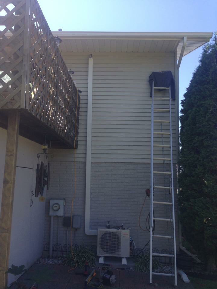 An outdoor mini-split air conditioning condenser unit installed on the side of a building by The Heating Guys in Fargo, ND.