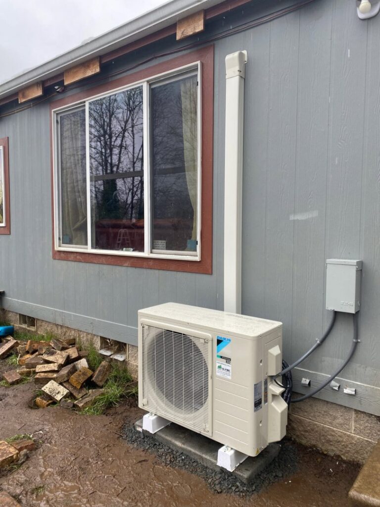 An installed Daikin mini-split AC outdoor unit next to a home by Alpine Heating in Eugene, OR.
