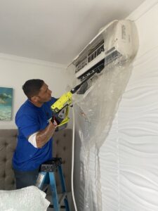 An Ultimate Air Conditioning technician performing a deep cleaning on a mini-split AC unit in Pearl City, HI