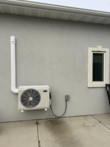 An outdoor Carrier mini-split air conditioning unit installed on a building wall by Golden Heating and Air LLC in Arvada, CO.