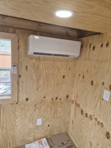 An indoor mini-split AC unit professionally installed on a plywood wall by Jesse's HVAC LLC in Newport News, VA.