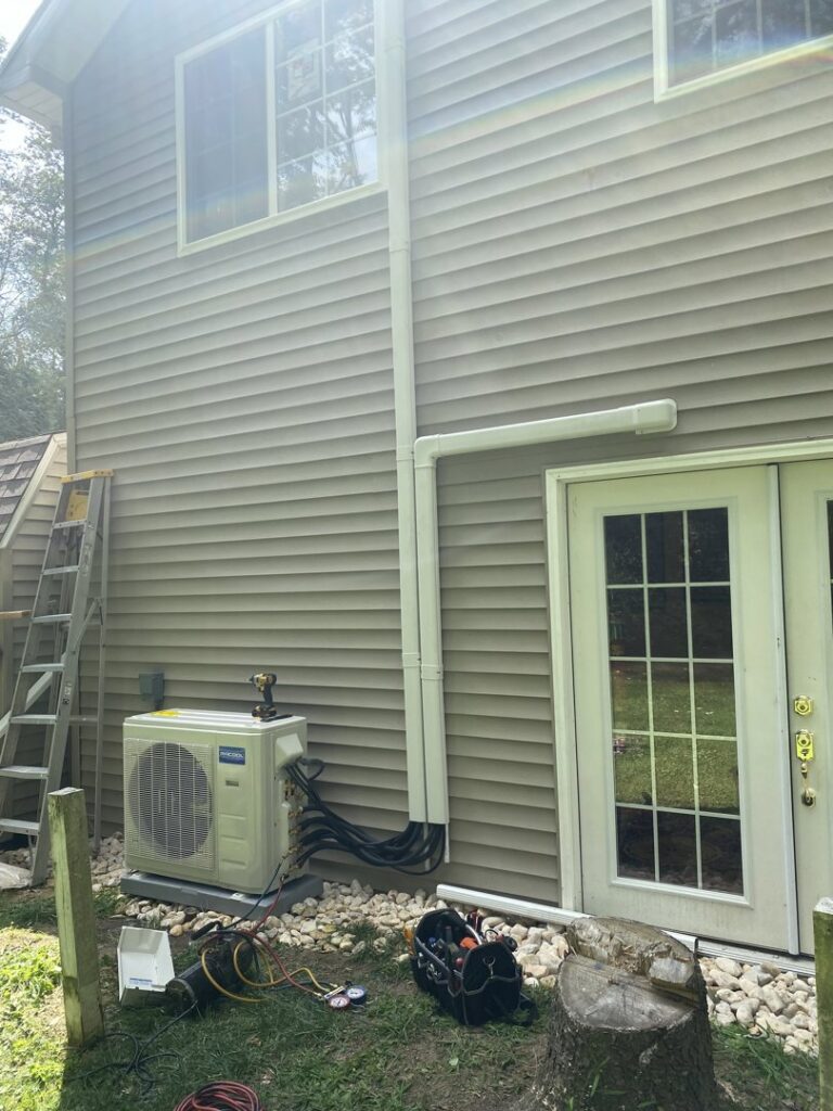 A mini-split AC unit installed outside a home with tools on the ground by Kane Heating & Air in Mountain Top, PA.