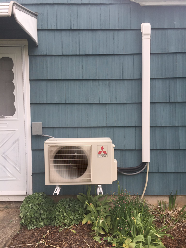 An outdoor Mitsubishi Electric mini-split AC unit professionally installed on a residential home by Spencer Heating & Air Conditioning in Norcross, GA.