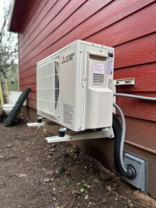 Outdoor mini-split condenser unit mounted on a red house wall, installed by GreenFlow Heating & Cooling in Tacoma, WA