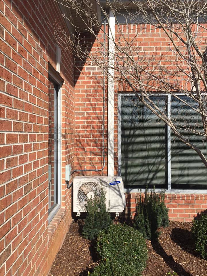 A mini-split condenser unit installed outside a brick building by A&A HVAC and Electrical LLC in Nashville, TN.