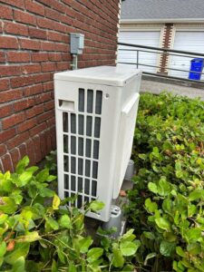 An outdoor mini-split condenser unit installed next to a brick wall by A's Heating and Cooling LLC in Portland, OR.