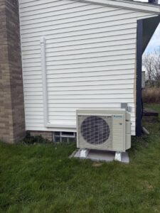 An outdoor mini-split condenser unit installed on the ground next to a house by My HVAC Guy in North Canton, OH.