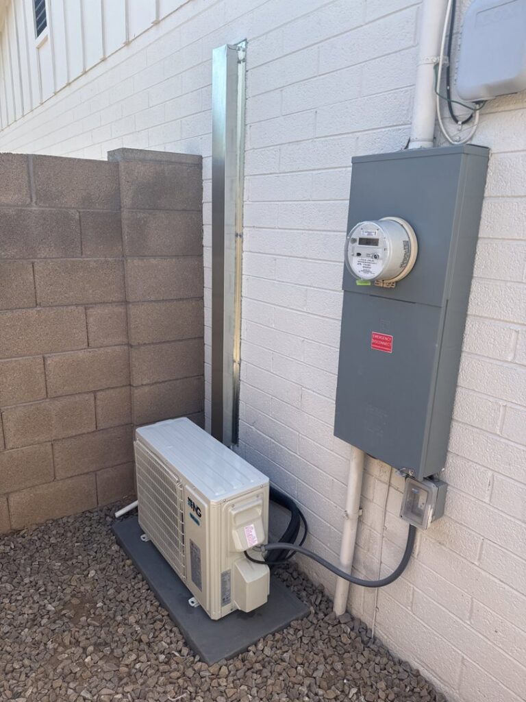 A mini-split condenser unit installed next to an electrical panel by Desert Heroes HVAC in Phoenix, AZ