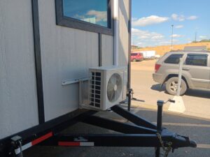 An outdoor mini-split condenser unit installed on a trailer, indicating mobile or specialized HVAC service by JJJ Techs Heating and Cooling in Kinzers, PA.