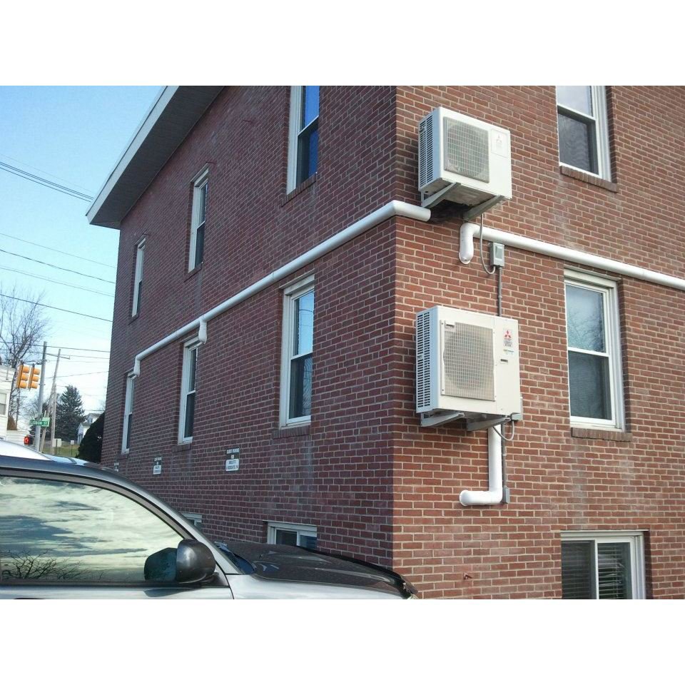 Two mini-split heat pump outdoor units installed on a brick building by Pro-Tech Refrigeration in Auburn, ME.
