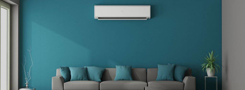 A white mini-split heat pump unit installed on a teal wall, serviced by Winks Heat Pump Cleanings in Bangor, ME