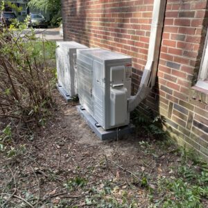 Two outdoor mini-split HVAC condenser units professionally installed next to a brick residential building by T & T HVAC in Amherst, OH.