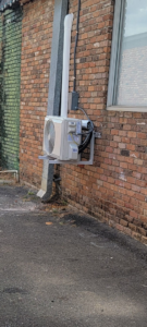 A newly installed mini-split HVAC outdoor unit mounted on a brick wall by ARKLA AIR LLC in Springhill, LA.