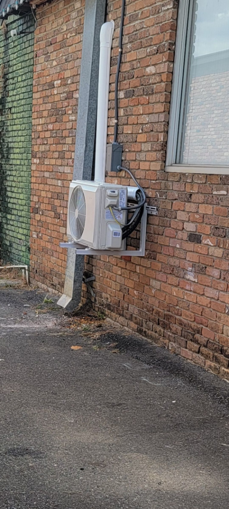 A newly installed mini-split HVAC outdoor unit mounted on a brick wall by ARKLA AIR LLC in Springhill, LA.