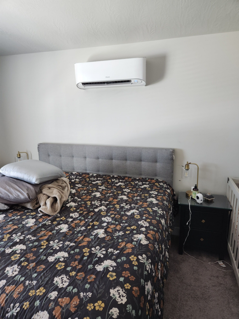 An indoor mini-split HVAC unit installed above a bed by Simple Valley Heating and Cooling in Orem, UT