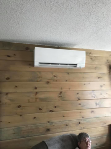 A mini-split HVAC indoor unit installed on a wooden wall in a room by R & R H.V.A.C in Knoxville, TN.