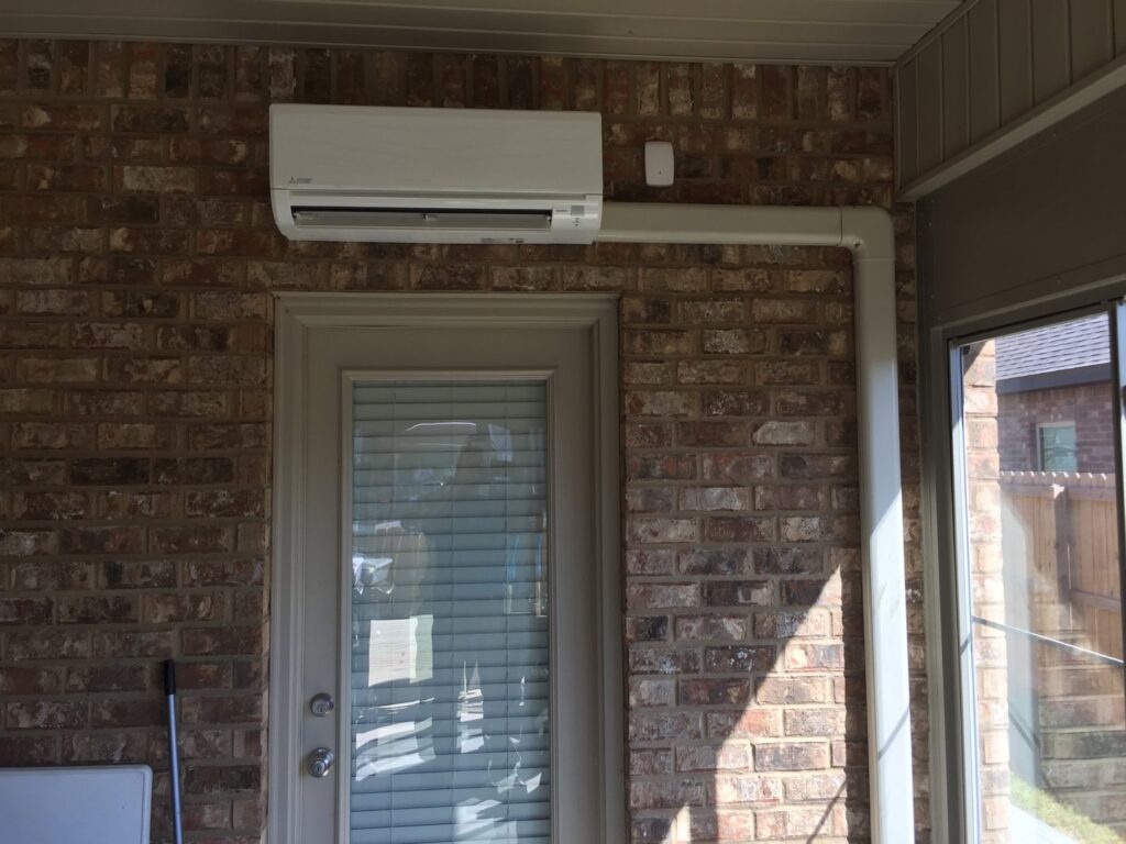 A mini-split indoor HVAC unit installed on a brick wall above a door by Anderson Mechanical Inc. in Pascagoula, MS