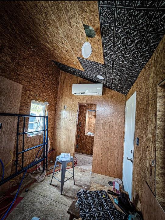 An indoor mini-split HVAC unit installed on a wall in a room under construction by Cool y Caliente HVAC Services in Bonner Springs, KS.