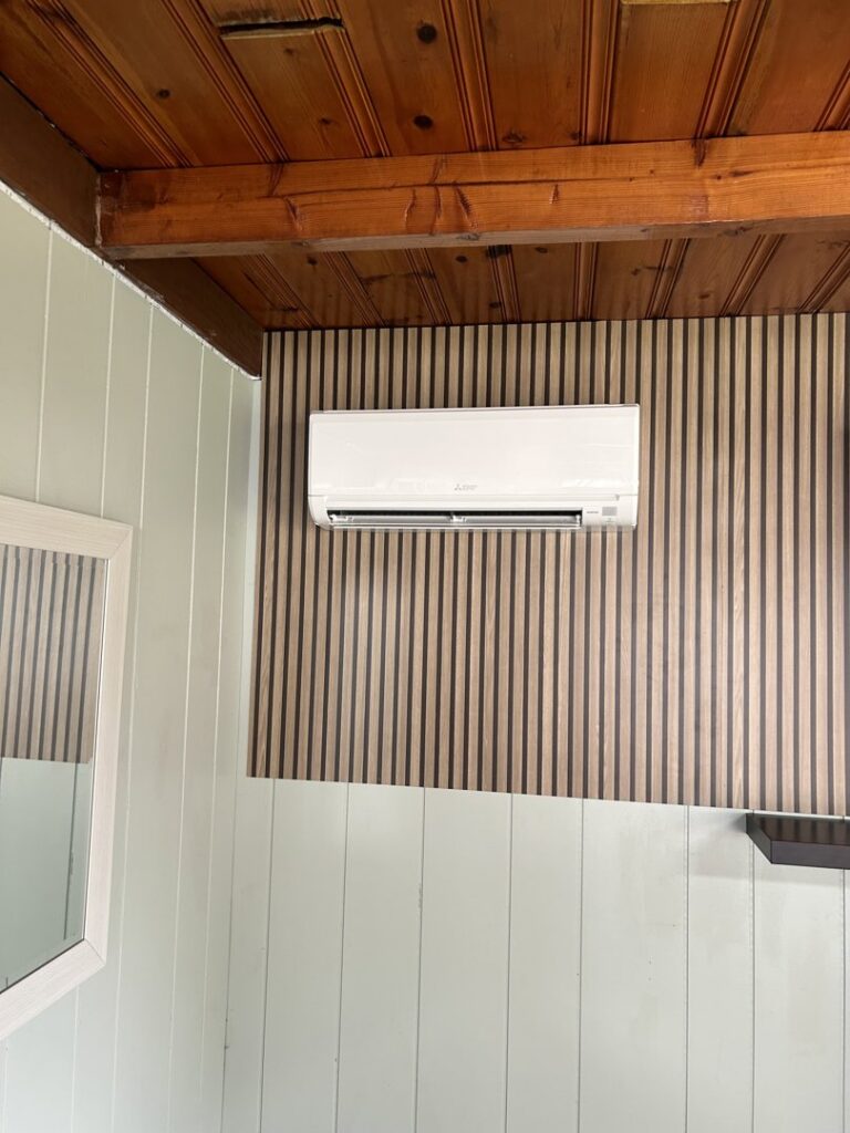 An indoor mini-split head unit installed on a decorative wood-paneled wall by Climate Diagnostics in Buffalo, NY.