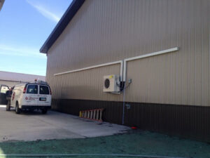 A mini-split air conditioning unit installation with The Heating Guys service van visible in Fargo, ND.