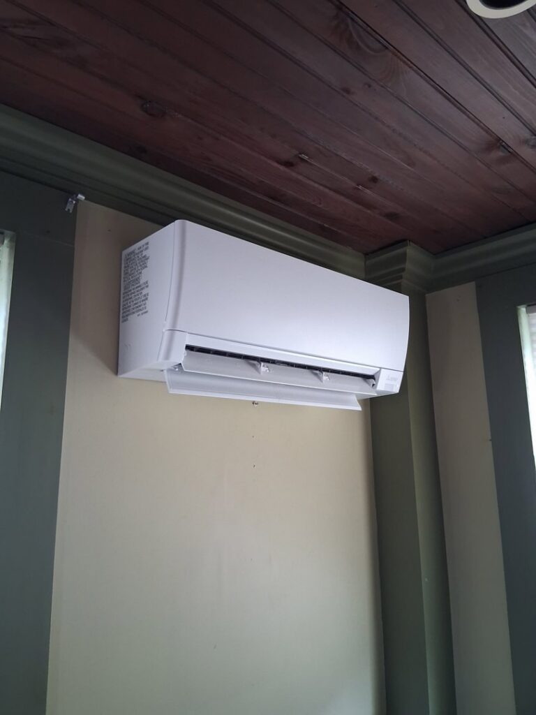 An indoor mini-split unit installed on a wall below a dark wooden ceiling, showcasing an HVAC installation by A&D Ductless LLC in Lunenburg, MA.