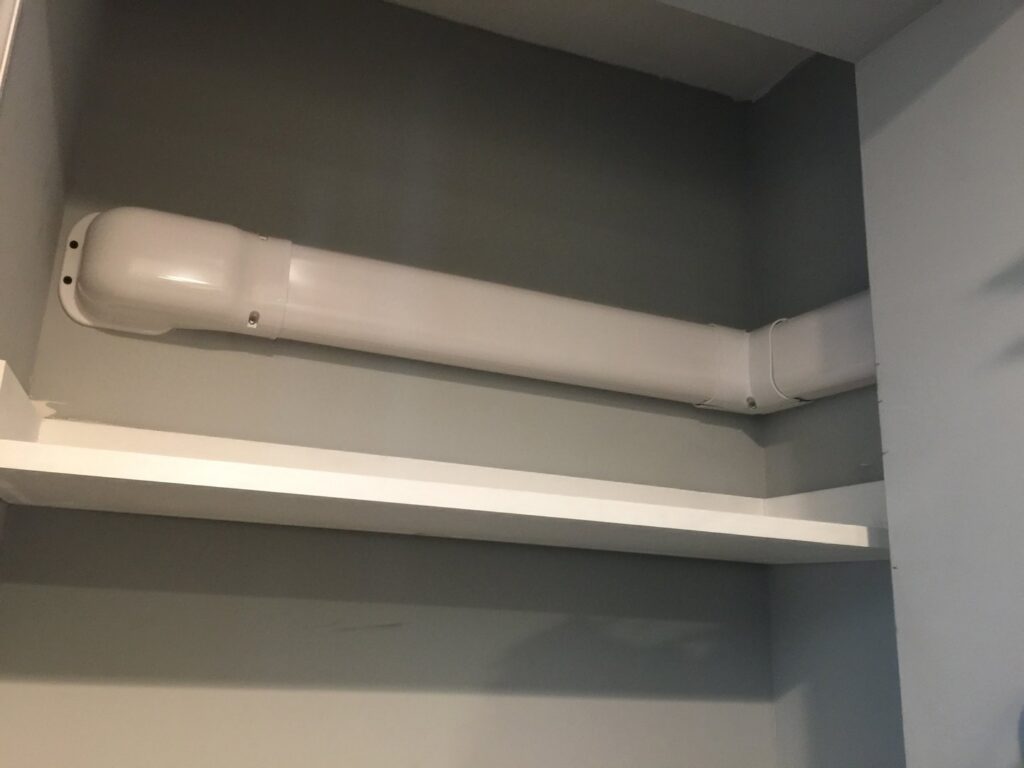 A neatly installed white line set cover for a mini-split system running along a wall in a closet by Green Air Heating&Cooling in Philadelphia, PA.