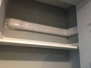 A neatly installed white line set cover for a mini-split system running along a wall in a closet by Green Air Heating&Cooling in Philadelphia, PA.
