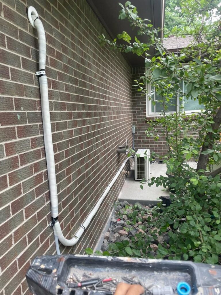 A mini-split line set installation running along a brick wall by National Heating & Cooling Company in Lakewood, CO.