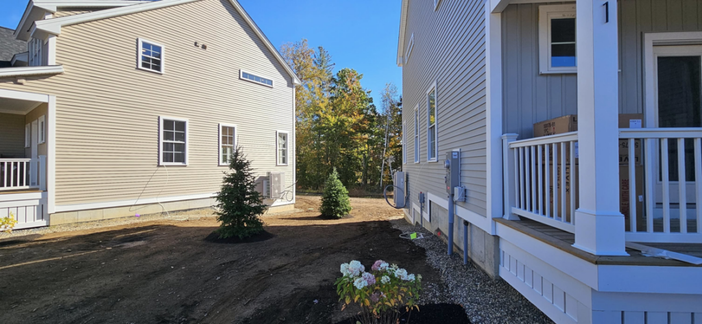 An outdoor mini-split condenser unit professionally installed on the side of a new home by Blue's Mini Splits LLC in Dover, NH