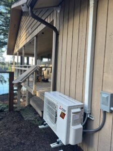 Outdoor mini-split condenser unit installed on the side of a house near a deck by GreenFlow Heating & Cooling in Tacoma, WA