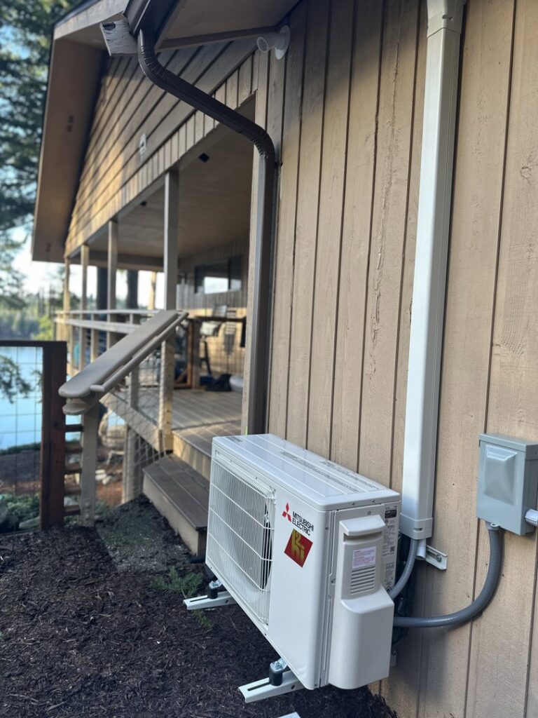 Outdoor mini-split condenser unit installed on the side of a house near a deck by GreenFlow Heating & Cooling in Tacoma, WA