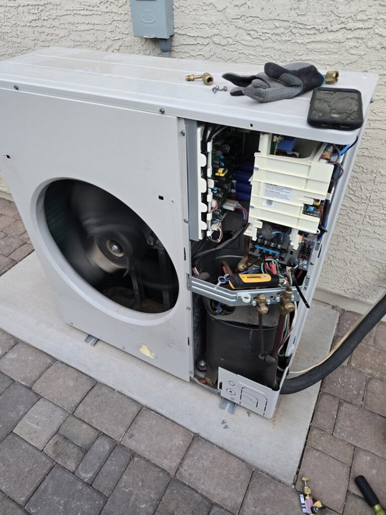 An open outdoor mini-split unit showing internal components during service by Quantum Cooling & Heating in Mesa, AZ.