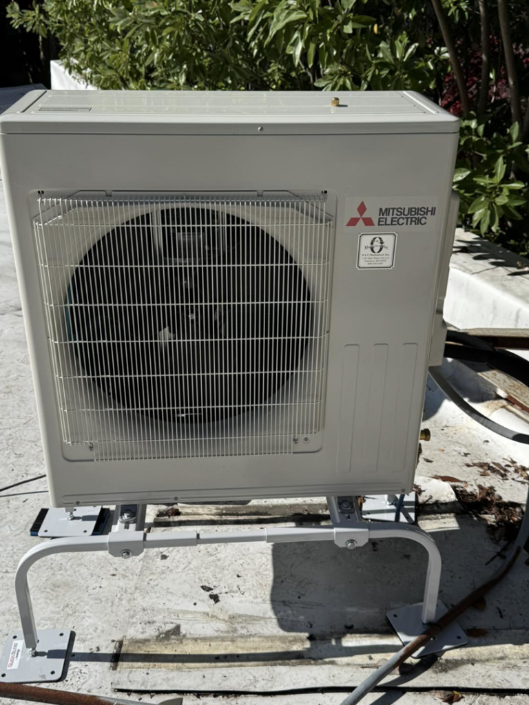 A Mitsubishi Electric mini-split outdoor condenser unit installed on an elevated platform by D and C Mechanical, Inc. in Tewksbury, MA.