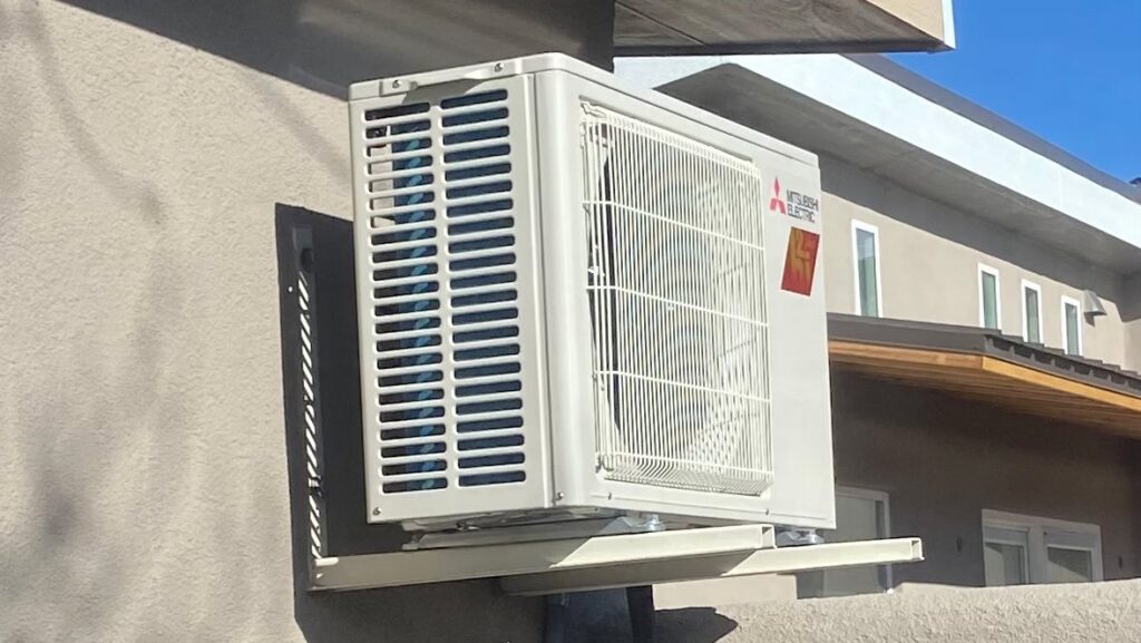 An outdoor Mitsubishi Electric mini-split condenser unit mounted on a wall bracket by Santa Fe Heating & Cooling LLC in Santa Fe, NM.