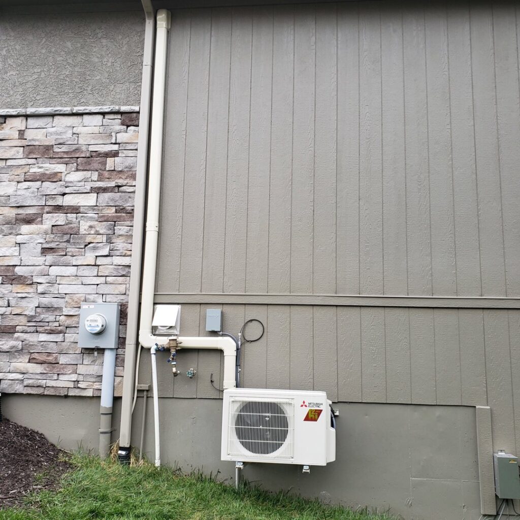 A Mitsubishi Electric mini-split outdoor unit installed by A-Team PHC on the side of a home in Olathe, KS.