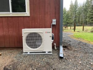 A Mitsubishi Electric mini-split outdoor unit installed against a red residential building by Climate Control Experts HVAC LLC in Federal Way, WA